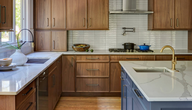 Modern Accents in Classic Kitchen Design Close-up of brushed brass handles and engineered stone surfaces that pair seamlessly with traditional wood cabinetry under layered lighting.