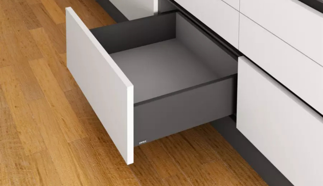 A mid-shot of white or oak shaker-style base cabinets featuring open soft-close drawers filled with cookware and utensils. Capture the smooth closing action to demonstrate convenience and quiet functionality.