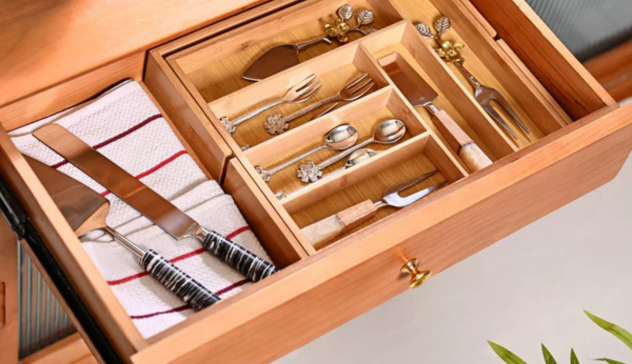 A close-up of a bamboo-lined utensil drawer featuring neatly arranged cutlery and cooking tools. Include drawer lighting or light reflection from above to highlight cleanliness and organization.